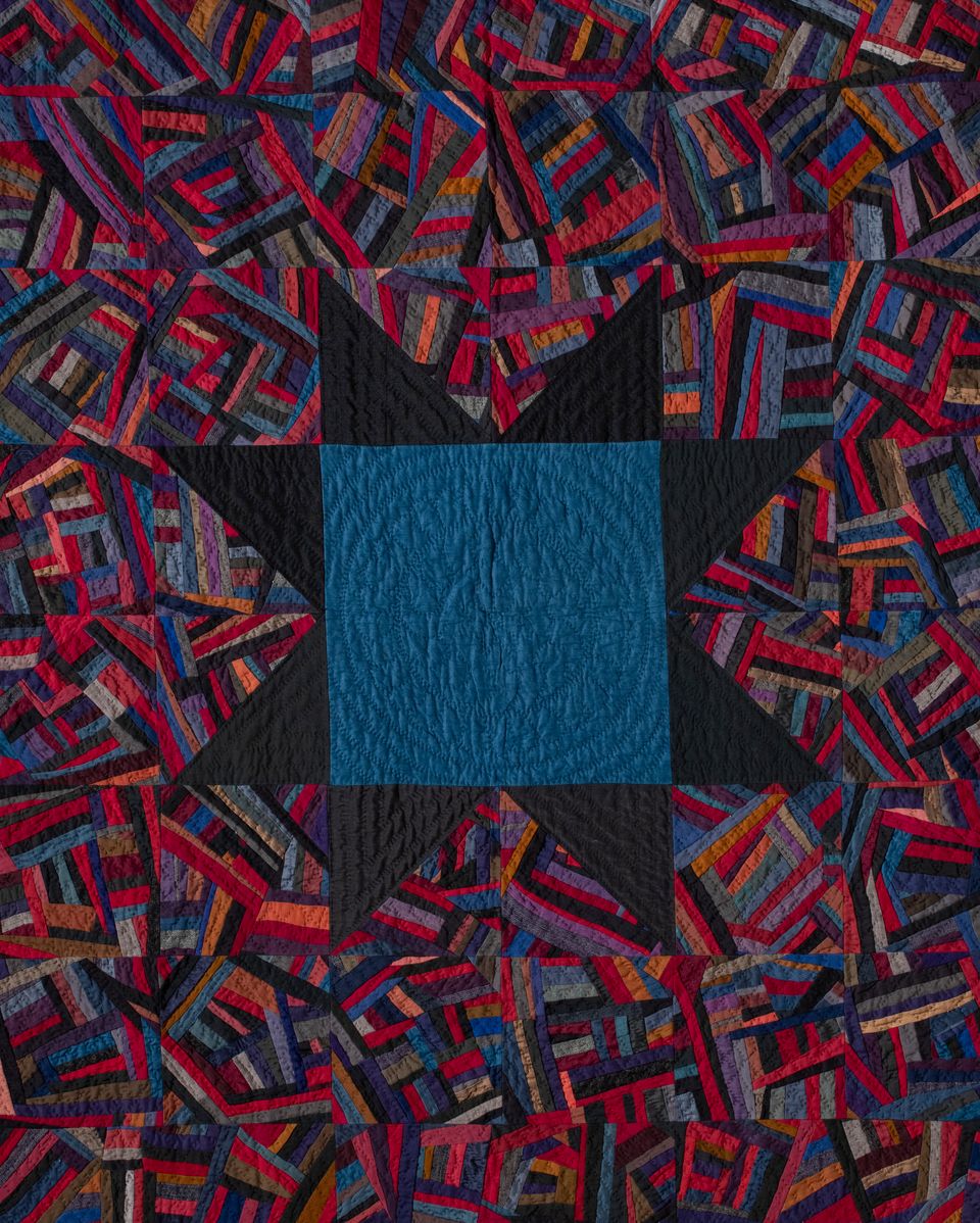Quilt with a colorful, abstract pattern. At the center is a dark blue square with a black star as its border.