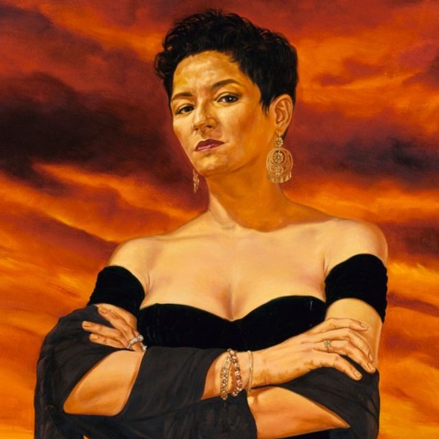 Woman with her arms crossed with a sunset background.