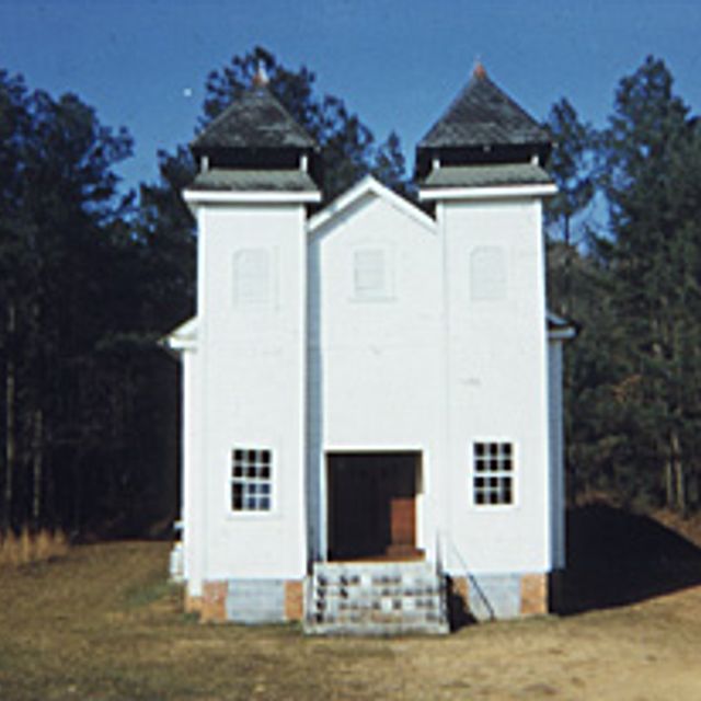 A painting of a white church in the woods