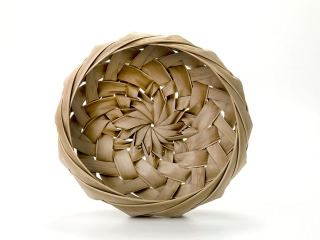 A basket that is small and round with a spiral pattern weave.