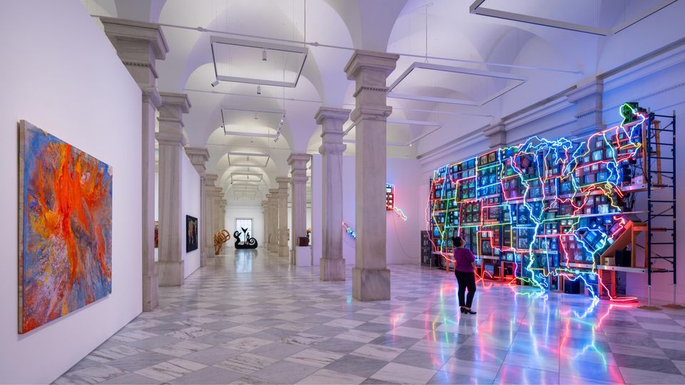 A marble gallery shows a neon sculpture of the United States across from an abstract painting