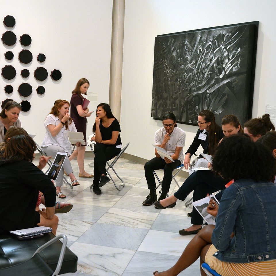 A photograph in gallery of a group of teachers sitting in chairs in discussion.