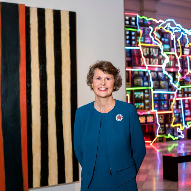 A photograph of a woman standing in front of artwork inside a museum.