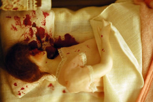 A photograph of a nutshell study of unexplained death showing a detail of a woman's murder scene in her bed.