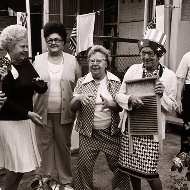 Group of senior citizens celebrating Fourth of July in front of a home.