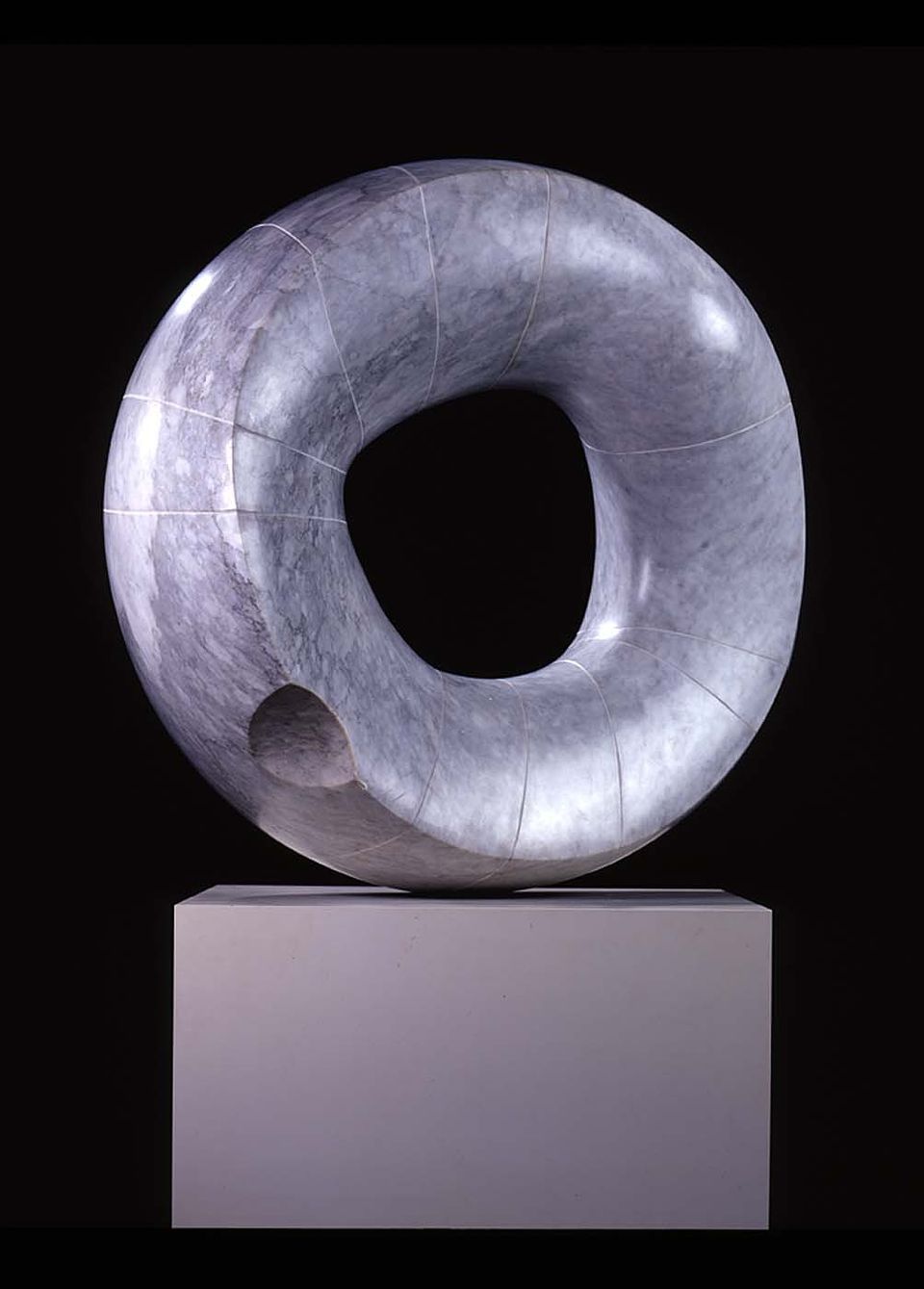 A round grey sculpture with a hole in the center  by Isamu Noguchi
