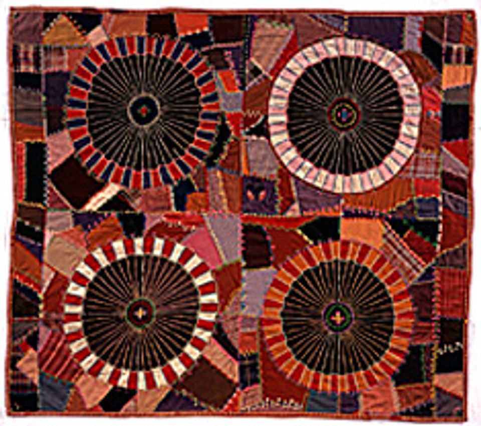 This is an embroidered wool quilt with red color tones and four circles. 