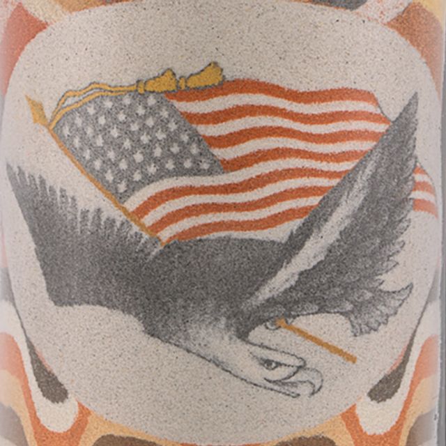 Detail of a sand bottle artwork showing an eagle carrying an American flag.