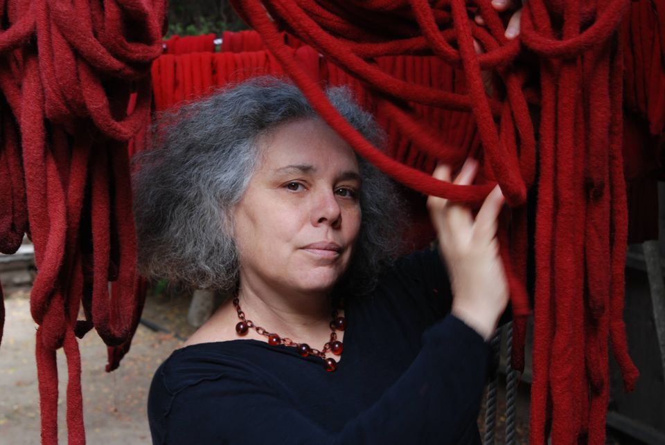 The artist Alison Saar stands in front of a red sculpture 