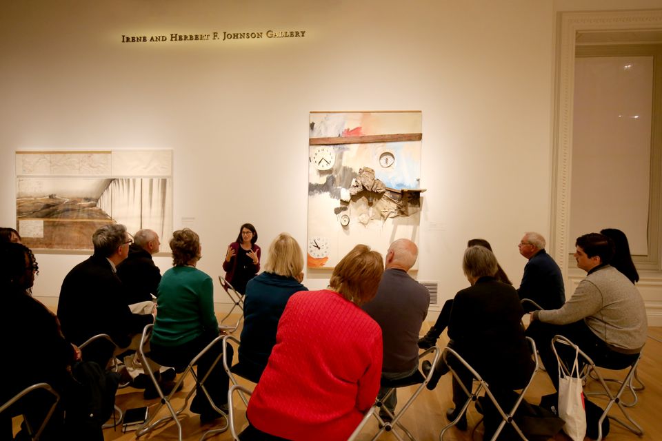 A photograph of a group in the museum sitting and discussing a painting.