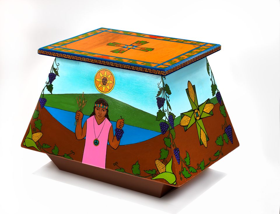 A colorful box with paintings on each side, including a figure holding crops and corn in a geometric motif.