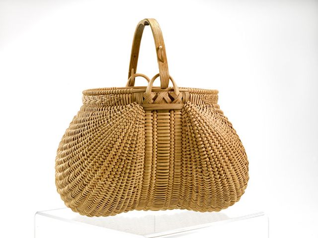 A basket that is circular, but the extension of the handle compresses the shape in the middle.