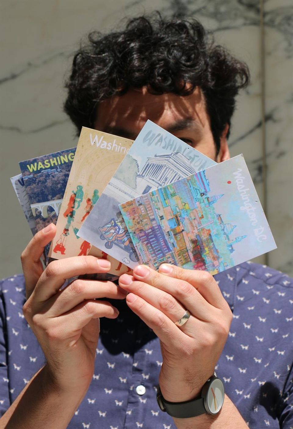 The artist holding some of his illustrated DC postcards