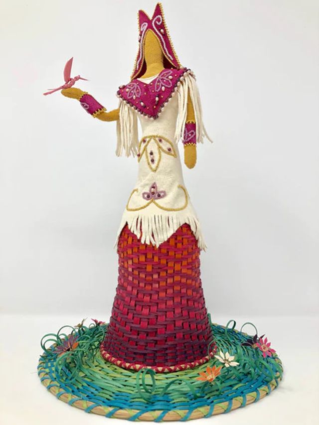A statute of a woman wearing a white, red, and pink outfit standing on a basket