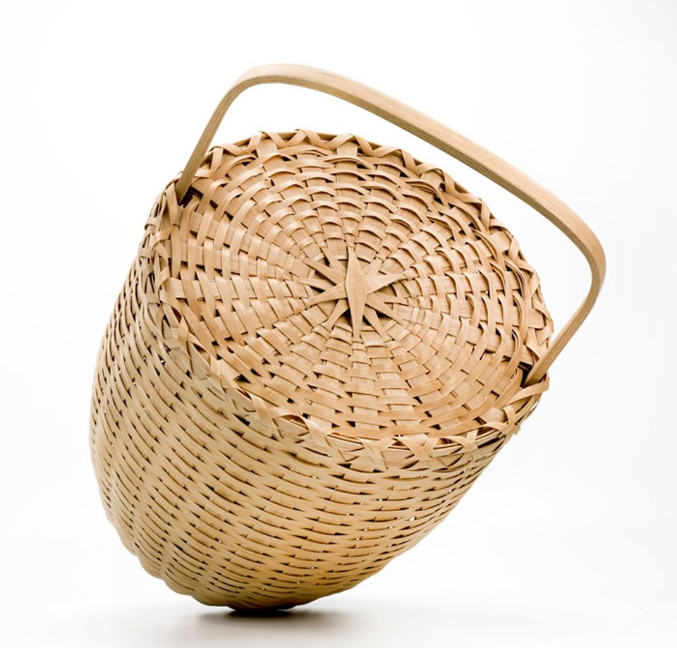 A basket with an oval shape and a lid and handle. 