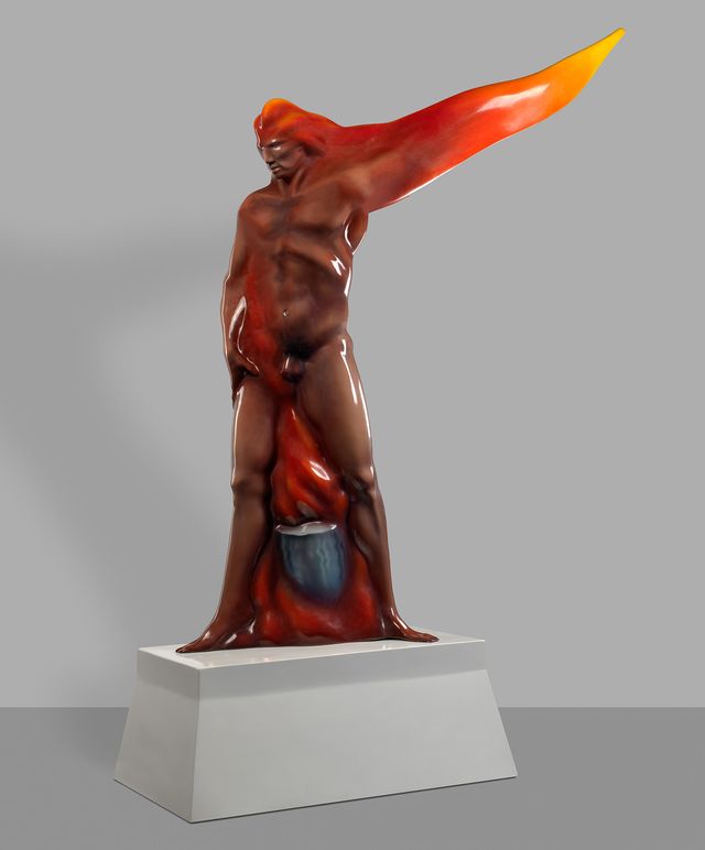 Artistic sculpture depicting a male figure with a dynamic, flowing form. The body is red and the outstretched arms extend diagonally from the back and fade from red to orange to yellow. The piece is displayed on a white pedestal against a neutral background.