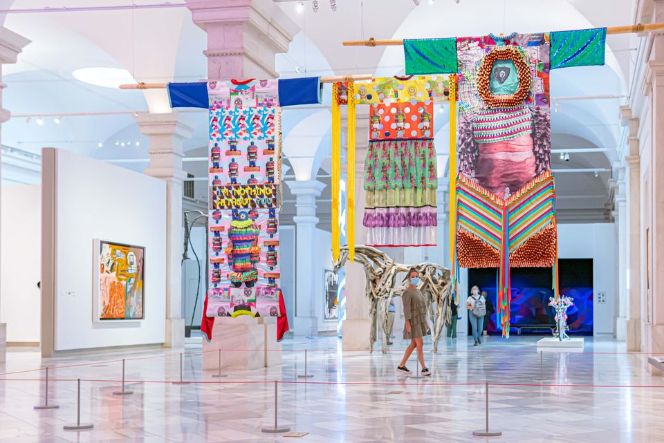 A visitor stands under multiple hanging artworks on the third floor of the Smithsonian American Art Museum