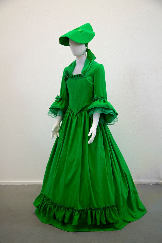 An image of a green dress with a colonial hat. 