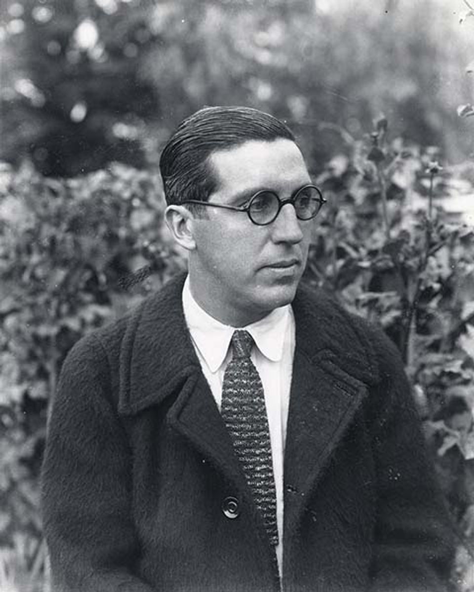 A photograph of a man in glasses with a coat and tie.