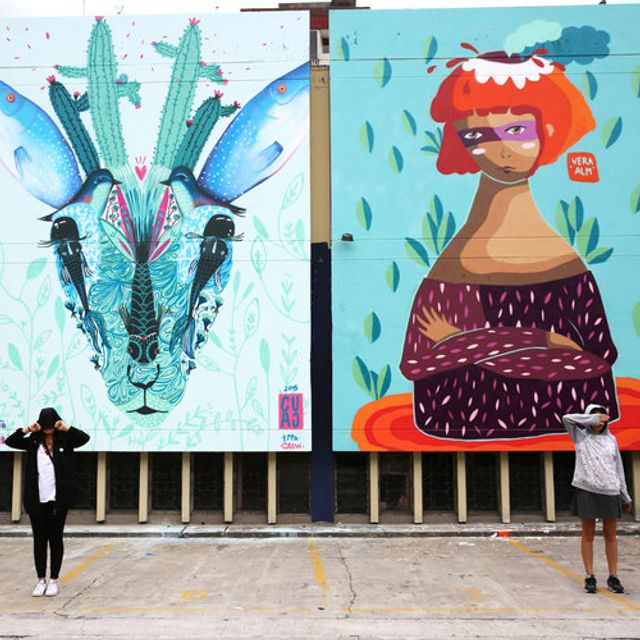 People stand in front of murals created by street artists