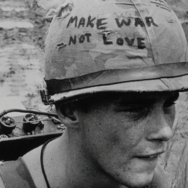 The face of soldier with a helmet that says "make war not love"