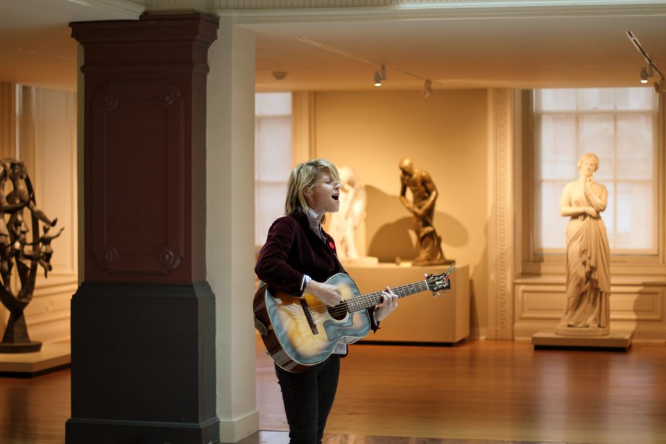 Olivia Mancini stands in the Luce Foundation Center and plays the electric guitar.