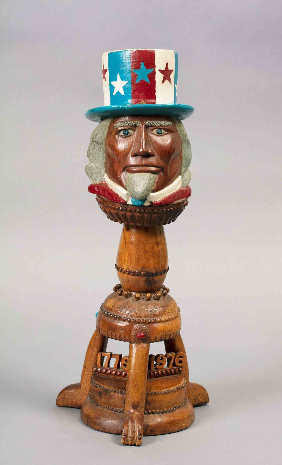 A carved and painted wooden sculpture topped by the head of Unlce Sam.