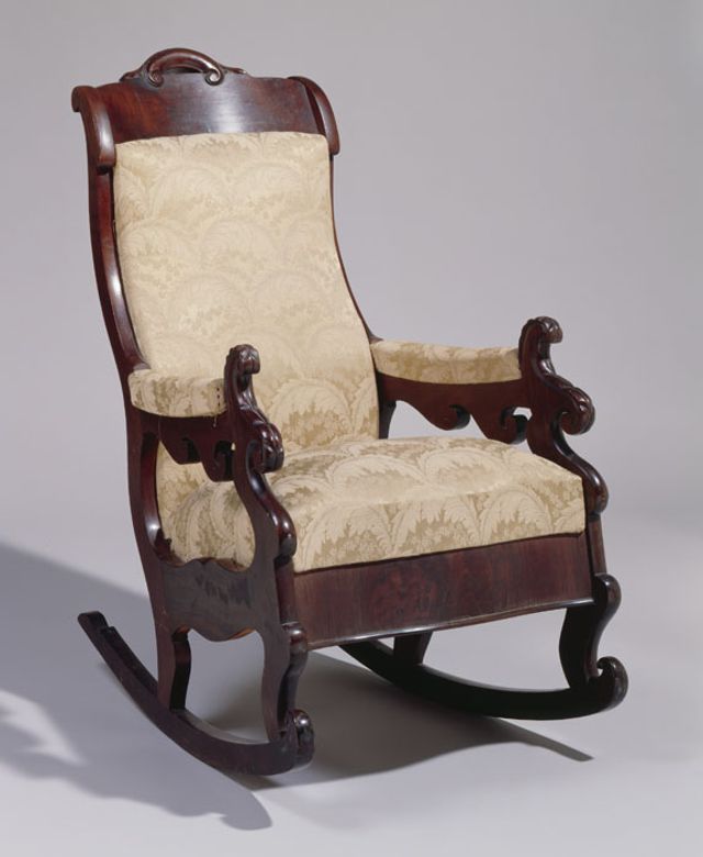 A mahogany rocking chair with creme upholstery.