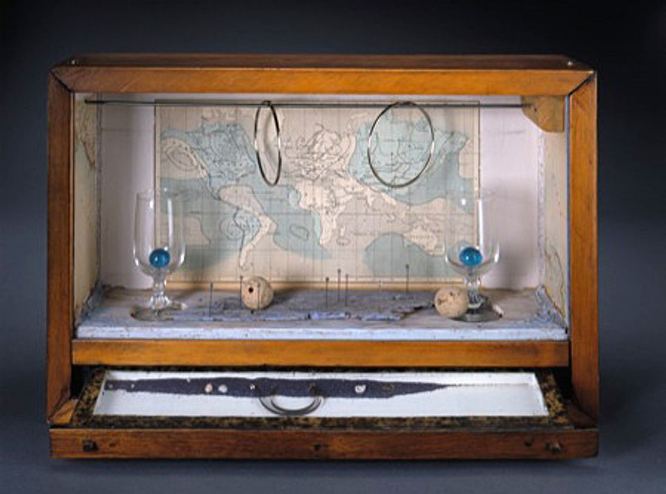 A box with a map in the background and two circles hanging from the top with two small glasses with blue balls inside.