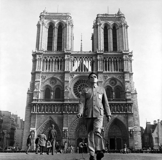 Photo of an Asian man with sunglasses, standing in front of a large cathedral in Paris.