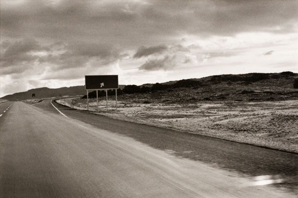 A photograph of a Utah landscape with an exit sign taken by automobile.