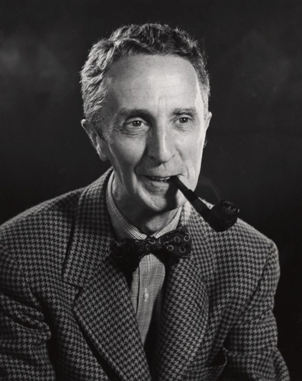 A black and white photo of Norman Rockwell smoking a pipe during the 1950s.