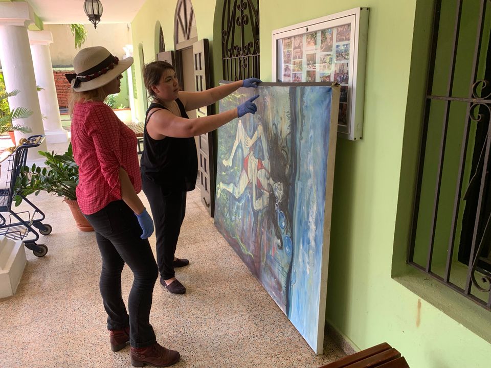An image of conservators looking at a painting outside of Casa Ulanga, Puerto Rico