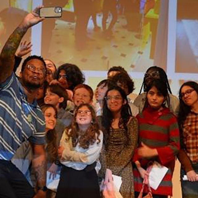 A group of students taking a selfie in front of a projected screen.
