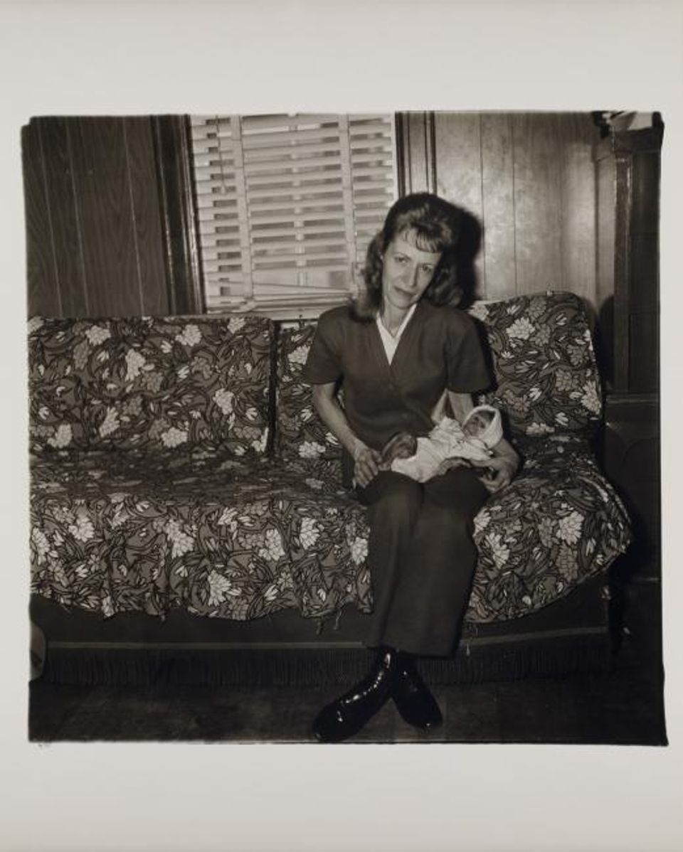 This is an artwork by Diane Arbus, showing a woman sitting on a couch and holding a monkey dressed as a baby