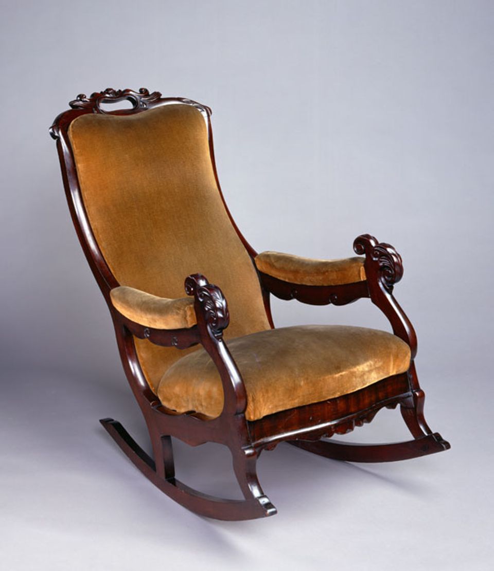 A mahogany rocking chair with yellow upholstery.