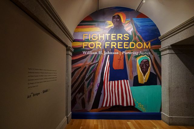 Entrance to a museum exhibition. The wall is covered in a mural depicting Harriet Tubman with the title "Fighters for Freedom: William H. Johnson Picturing Justice." 