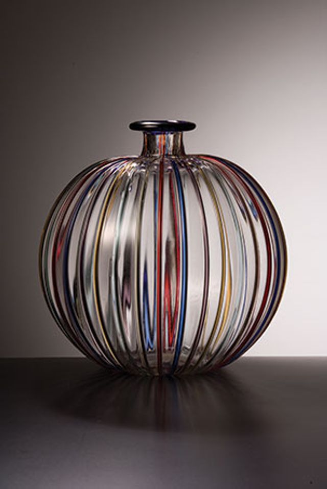 A clear glass vessel with rainbow colors painted in stripes down the side.