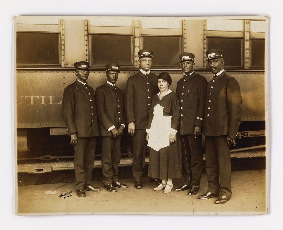 A black and white photograph of a group of porters standing in front of a train.