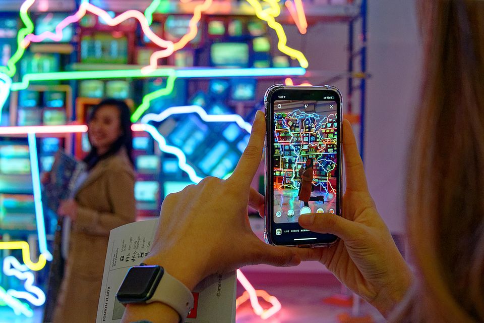 A photograph of a person taking a photo with a cell phone.