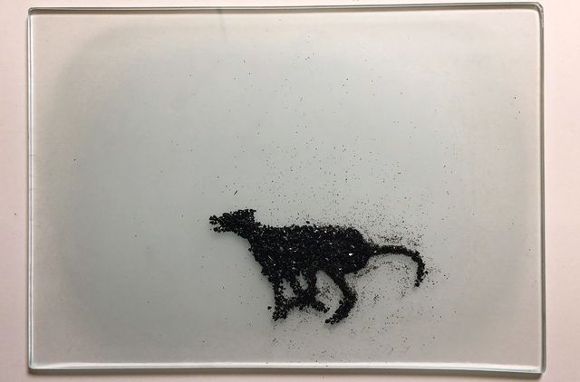 An artwork made of glass with a black greyhound dog. 