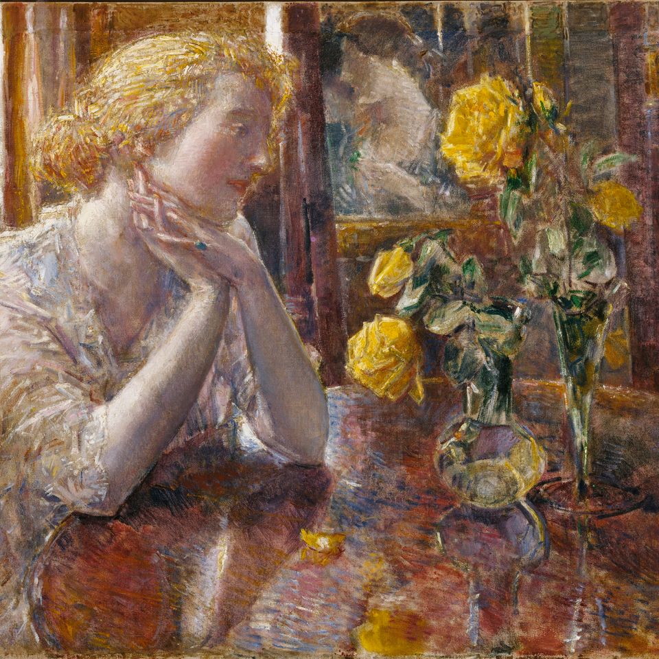 A woman sitting at a table looking at yellow flowers.