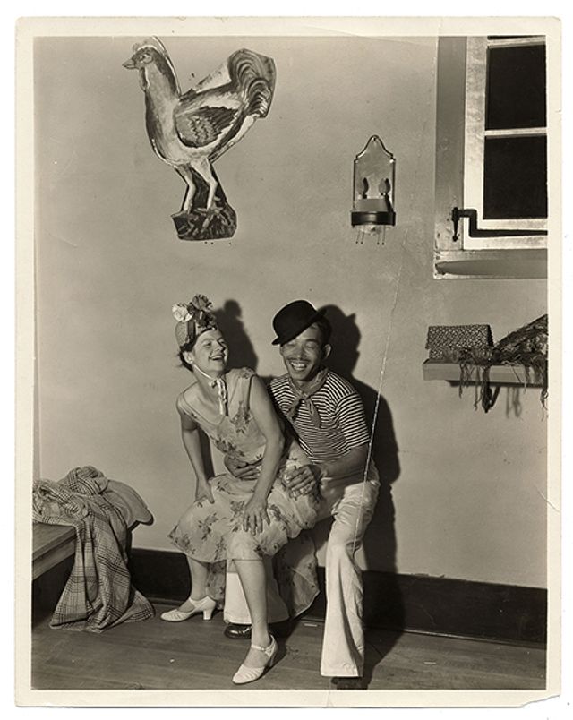 A photograph of a man and woman sitting on a chair laughing.