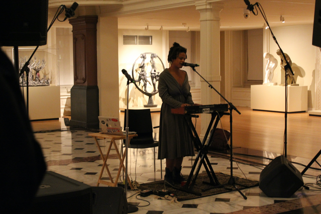 Jenna Camille stands in the Luce Foundation Center playing a keyboard and singing into a microphone.