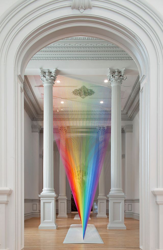 A floor to ceiling photograph of colorful string creating a rainbow affect.