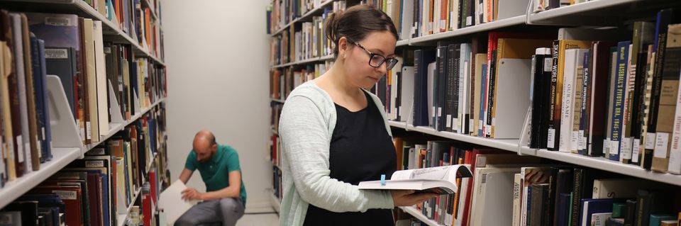 Two researchers in library stacks
