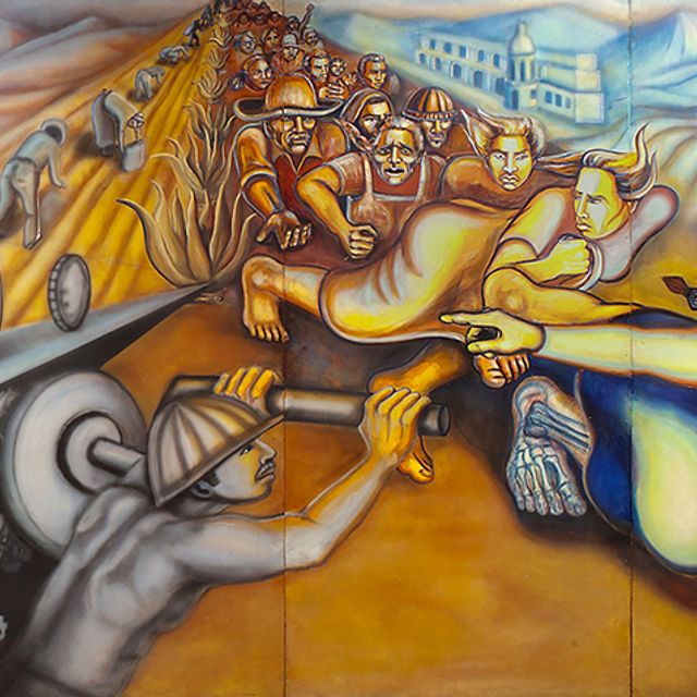 Detail of a mural showing an indigenous woman at the  forefront of a scene of farmworkers