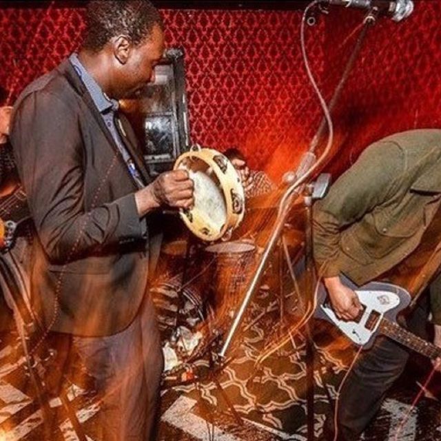 Two people in a band playing the guitar and the tambourine.