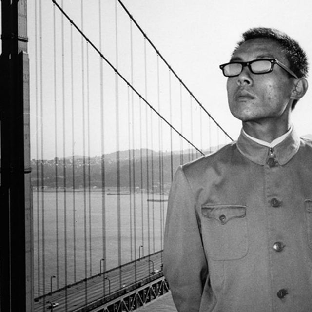 A man in a Mao suit standing in front of the Golden Gate Bridge