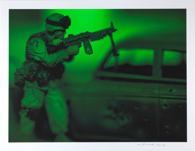 A photograph in green of a man with a gun.
